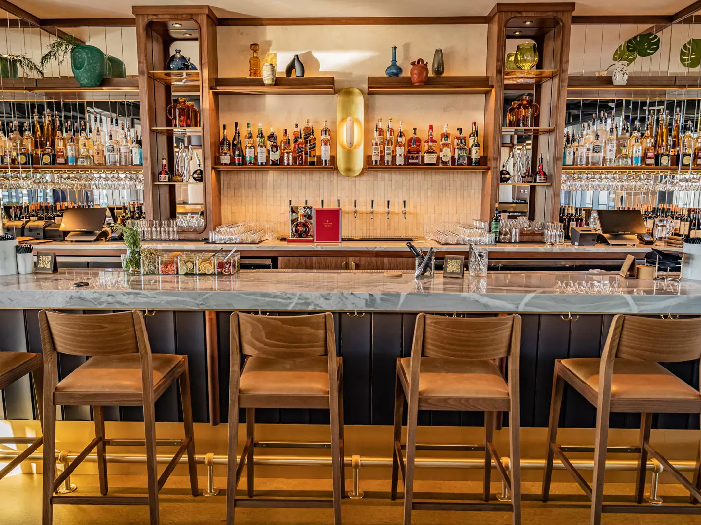 image showing stools at a bar with dozens of liquor bottles on display